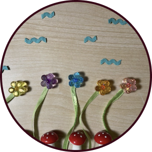 A meadow scene of beads and ribbons, the flowers are bending in the wind