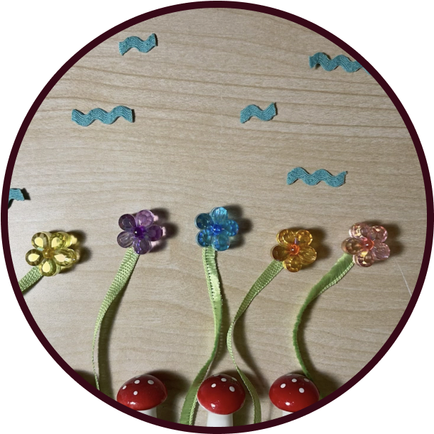 A meadow scene of beads and ribbons, the flowers are bending in the wind