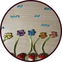 A meadow scene of beads and ribbons, the flowers are bending in the wind